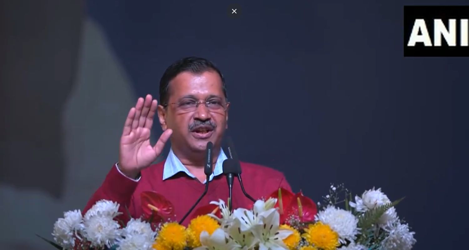 Arvind Kejriwal Delhi Chief Minister wearing a red sweater while speaking to people at a public rally
