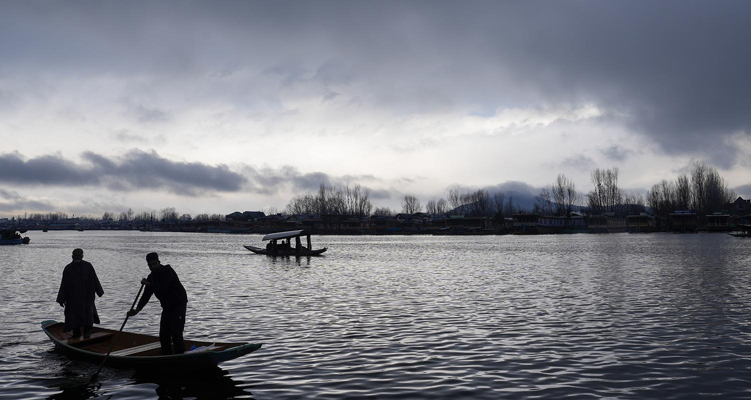 In Srinagar, boatmen skillfully navigate Dal Lake's waters amidst the rain. 