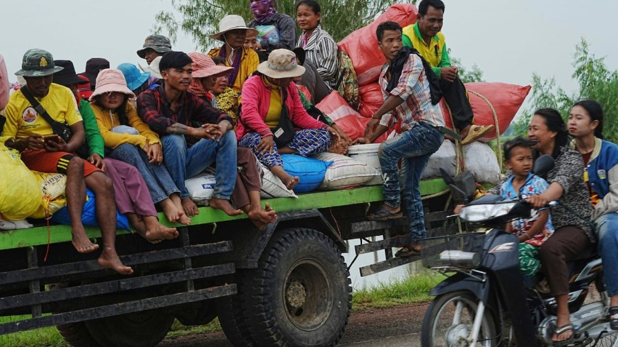 Cambodians sit on a cart of a tractor as they take refuge 