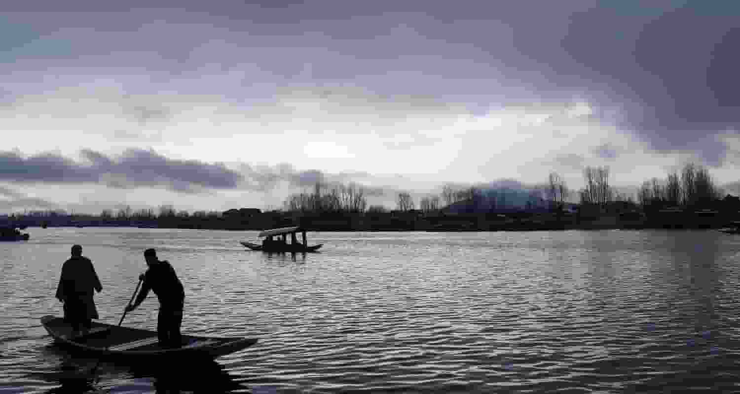 In Srinagar, boatmen skillfully navigate Dal Lake's waters amidst the rain. 