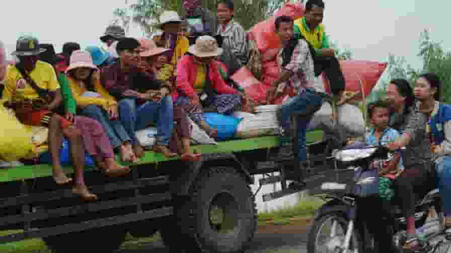 Cambodians sit on a cart of a tractor as they take refuge 